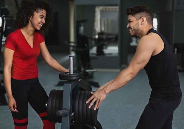 Chica atleta afroamericana hablando con el entrenador y tomando un descanso después del entrenamiento en el gimnasio