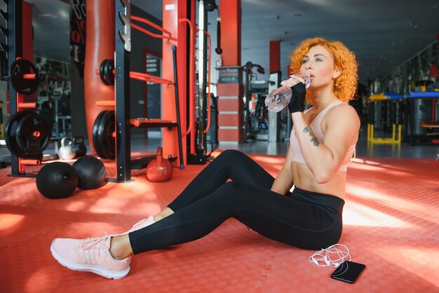 Chica atlética con agua en las manos en el gimnasio