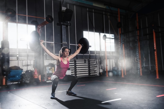 chica atlética hace ejercicio en el gimnasio con una barra