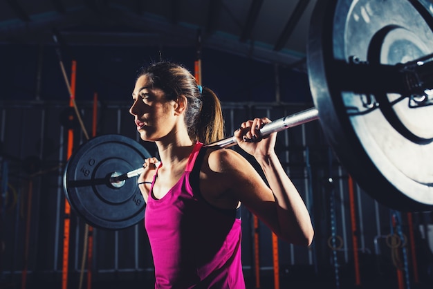 chica atlética hace ejercicio en el gimnasio con una barra