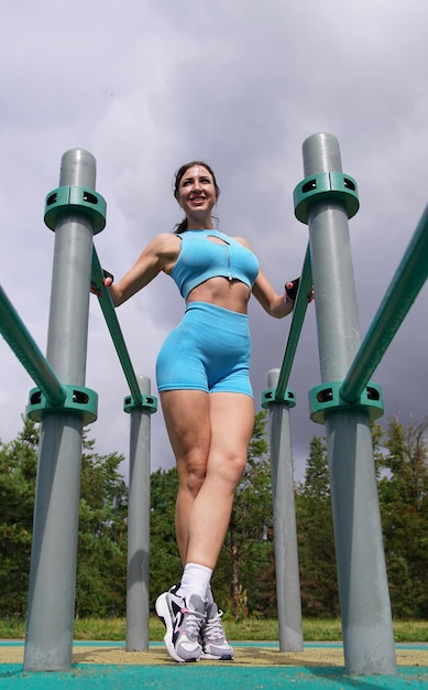 Chica atlética sexy en forma en buena forma perfecta con músculos joven mujer feliz culturista es entrenar entrenar al aire libre gimnasio al aire libre en verano Culturismo fitness estilo de vida saludable Foto vertical