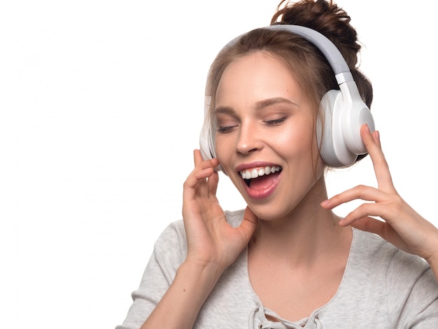 Chica atractiva con auriculares en pared blanca