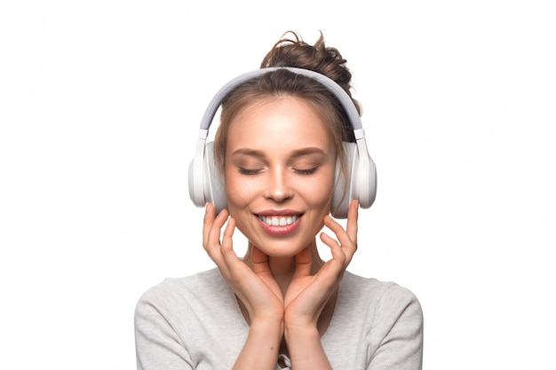 Chica atractiva con auriculares en pared blanca