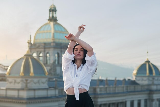 Una chica atractiva con una camiseta blanca y un cardigan está en el techo