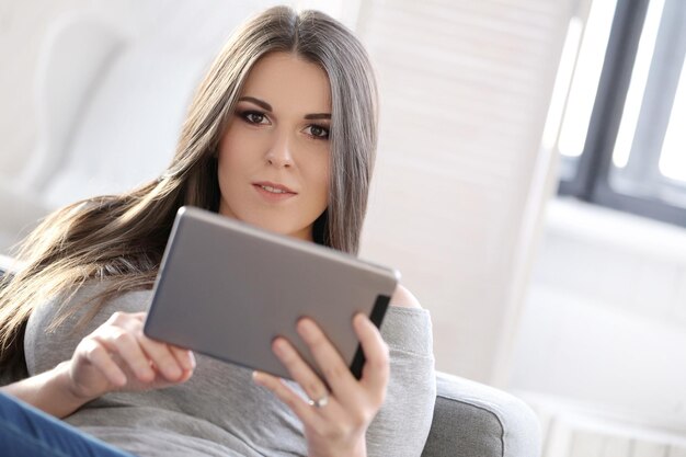 Chica atractiva en casa trabajando en su tableta