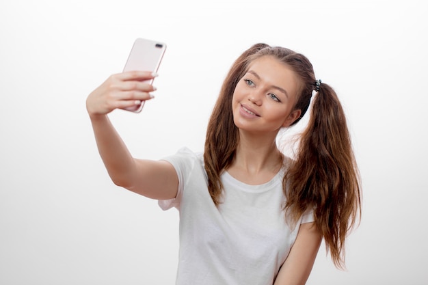 Chica atractiva con dos divertidas colas de caballo tomando fotos de sí misma