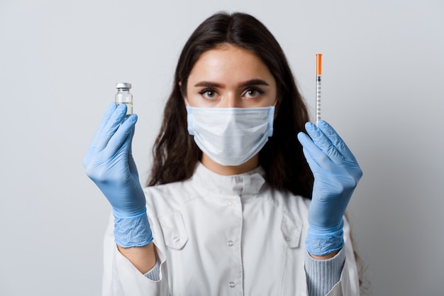 Chica atractiva en guantes médicos con jeringa y medicación. Doctor sosteniendo la vacuna contra el coronavirus. Vacunación Covid-19. Detener la cuarentena.