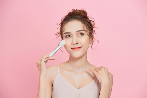 Chica atractiva haciendo maquillaje aplicando cosméticos de moda de maquillaje de cara de roygemon