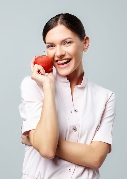 Una chica atractiva tiene una manzana roja en su mano delante de su rostro