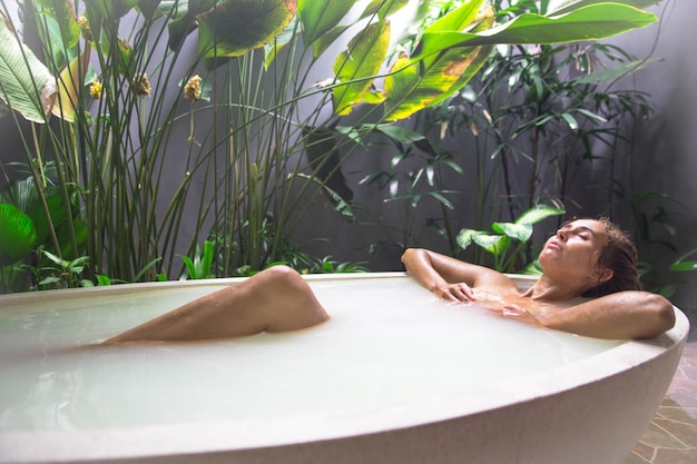 Chica atractiva toma tratamientos de spa de baño de leche para la piel