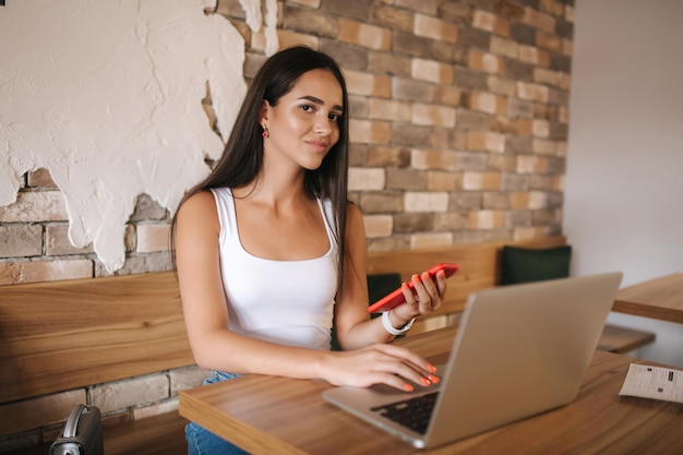 Chica atractiva trabajando en la computadora portátil en el café hermosa chica usando la computadora para el trabajo chica bebiendo