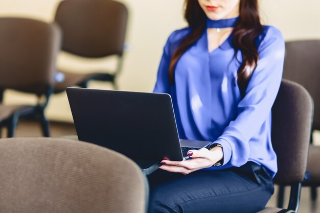 Chica en auditorio trabaja con laptop