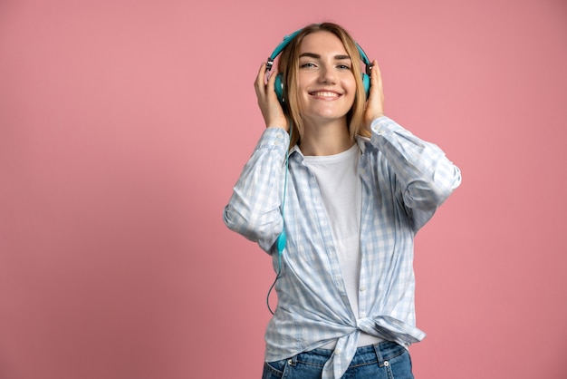 chica en auriculares aislado en rosa