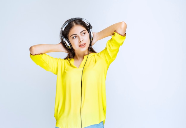 Chica con auriculares manteniendo la calma y disfrutando de la música.