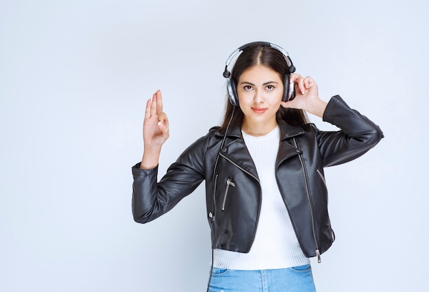 Chica con auriculares mostrando signo de disfrute.