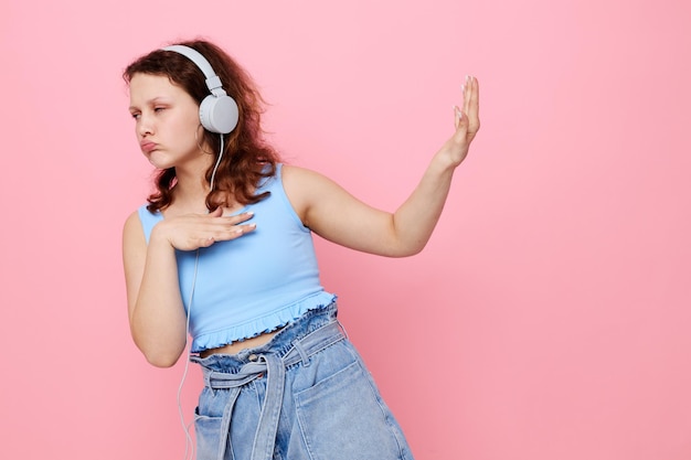 Chica con auriculares movimiento de baile entretenimiento fondo rosa inalterado