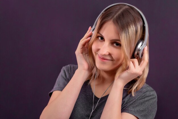 Chica en auriculares sonriendo y escuchando música