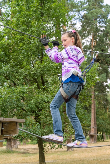 Chica en aventura escalando el parque high wire