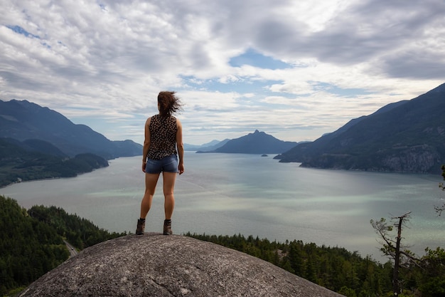 Chica aventurera escalando una montaña durante un vibrante día de verano