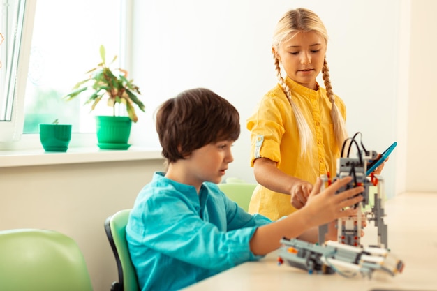 Chica ayudando a su compañero de clase a construir un robot