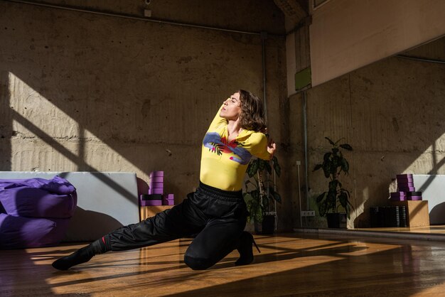 Una chica baila una danza contemporánea en un estudio iluminado por el sol