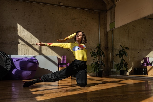 Una chica baila una danza contemporánea en un estudio iluminado por el sol