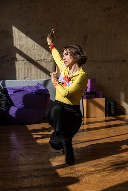 Una chica baila una danza contemporánea en un estudio iluminado por el sol