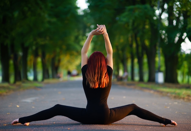 Chica bailando en un cuerpo negro en el jardín de verano.