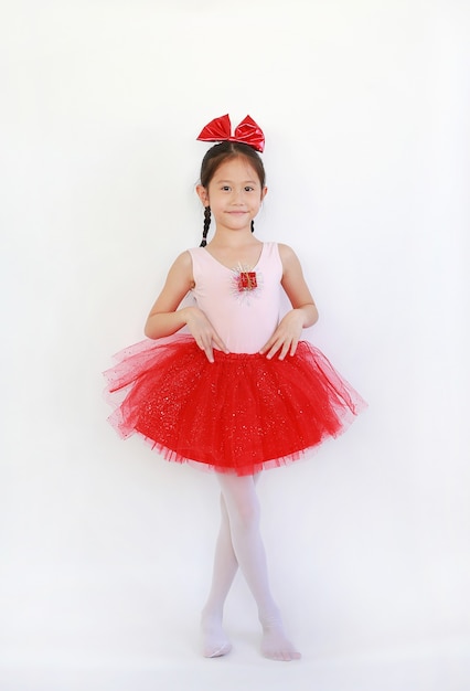 Chica bailarina de ballet asiática en falda tutú rosa-rojo sobre blanco