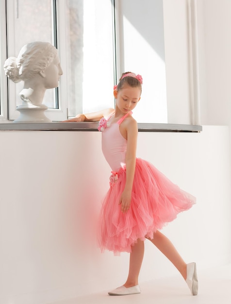 Chica bailarina en un tutú junto a la ventana