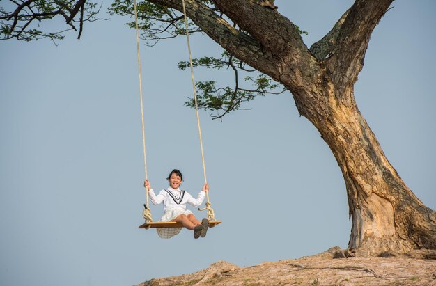 Foto una chica balanceándose contra el cielo despejado