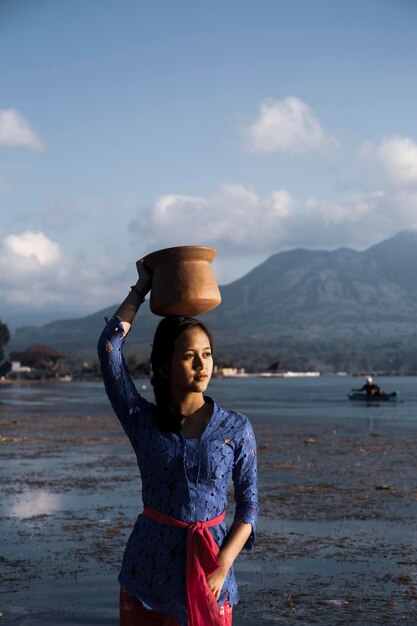 Chica balinesa con traje tradicional lleva agua en una jarra