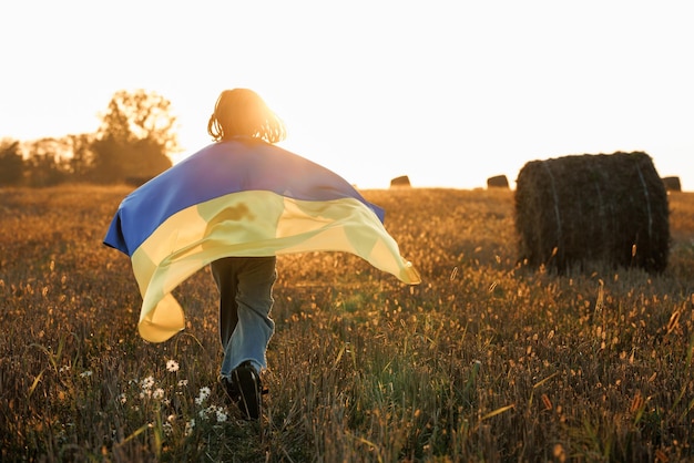 Foto chica con bandera de ucrania corriendo en el campo chica patriótica volando bandera ucraniana ucrania agosto