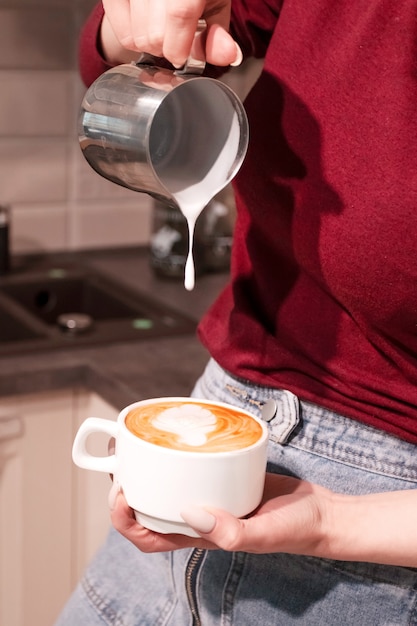 Chica barista haciendo café con leche arte.