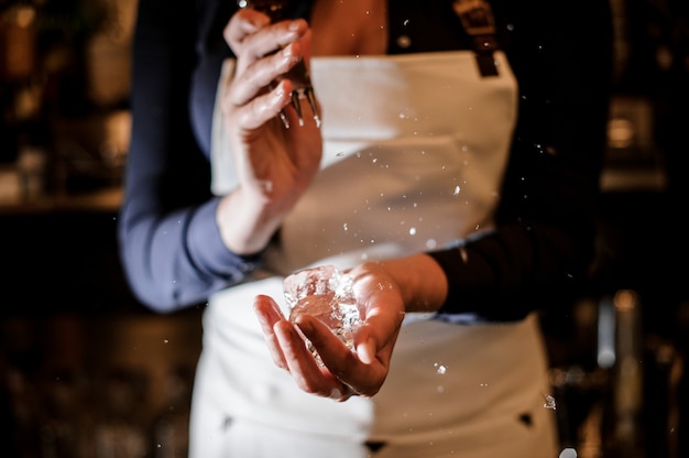 Chica de barman aplastando un trozo de hielo