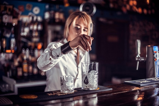 Chica barman formula un cóctel en la cervecería