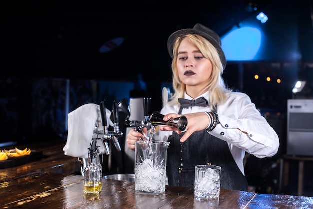 Chica barman formula un cóctel detrás de la barra