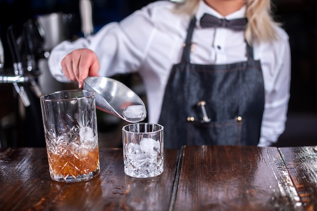 Chica barman hace un cóctel en la cervecería