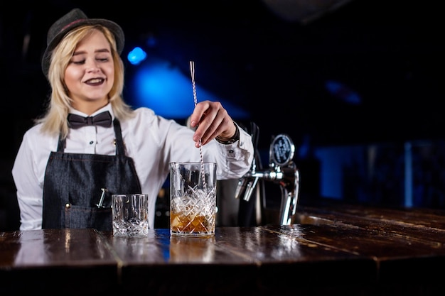 Foto chica barman mezcla un cóctel en la brasserie