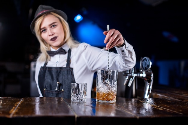 Chica barman prepara un cóctel en la olla