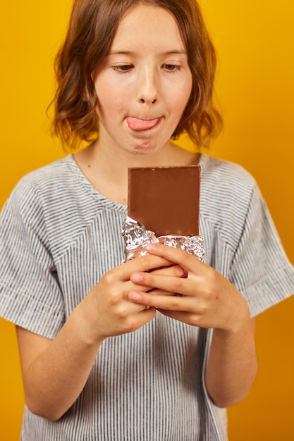 Chica bastante adolescente con una barra de chocolate aislada