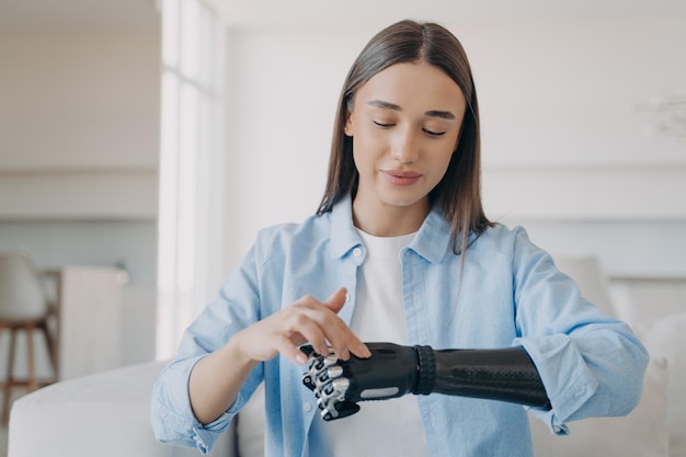 Chica bastante discapacitada ajustando su brazo protésico biónico tocando el panel sensorial de la mano artificial