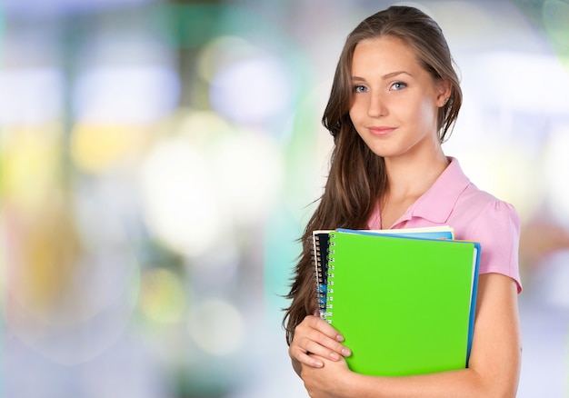 Chica bastante joven estudiante con libro sobre fondo