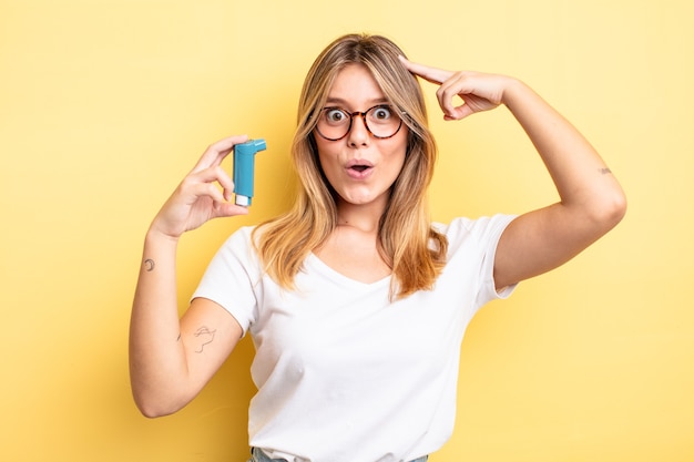 Chica bastante rubia que parece feliz, asombrada y sorprendida. concepto de inhalador para el asma