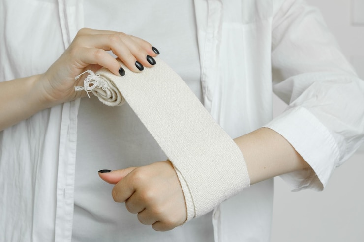 Foto una chica con una bata blanca muestra cómo vendar un brazo adolorido con una venda elástica, una herida en el brazo y una prohibición