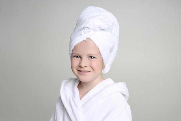 Chica con una bata blanca y una toalla en la cabeza después de una ducha y lavarse el pelo. Cosmética infantil y cuidado de la piel, Tratamientos de Spa. Cabello limpio y hermoso. Rusia Sverdlovsk, 20 de agosto de 2019