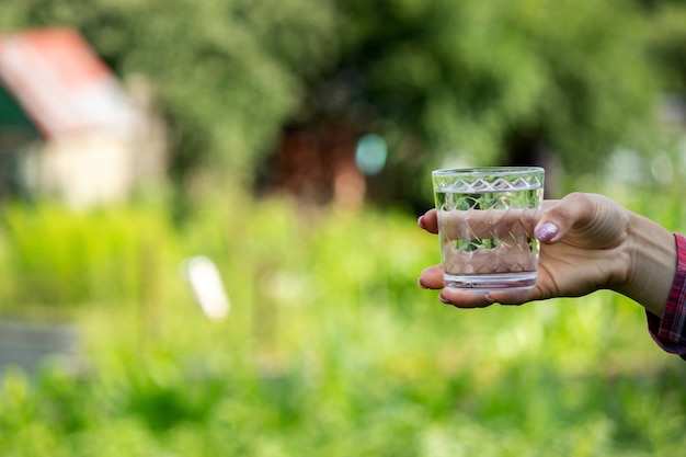 Chica bebe agua de un vaso, al aire libre. Enfoque selectivo