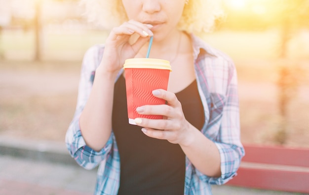 Foto chica bebiendo café de un vaso de papel a través de una pajita