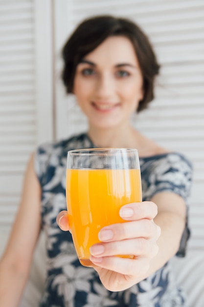 Foto chica bebiendo jugo de naranja en el desayuno en la cama