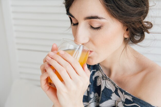 Chica bebiendo jugo de naranja en el desayuno en la cama